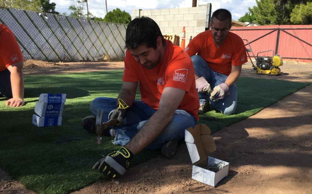 Home Depot volunteers install turf to make a play area for the veteran homeowner’s foster children, a project organized through the HandsOn Greater Phoenix Veteran Home Improvement Program.