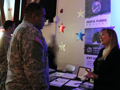 At a 2015 Veterans Day event, Gail Soffer speaks with an active-duty service member about doing a Mindful Warrior Project training for his soldiers at a local base. 