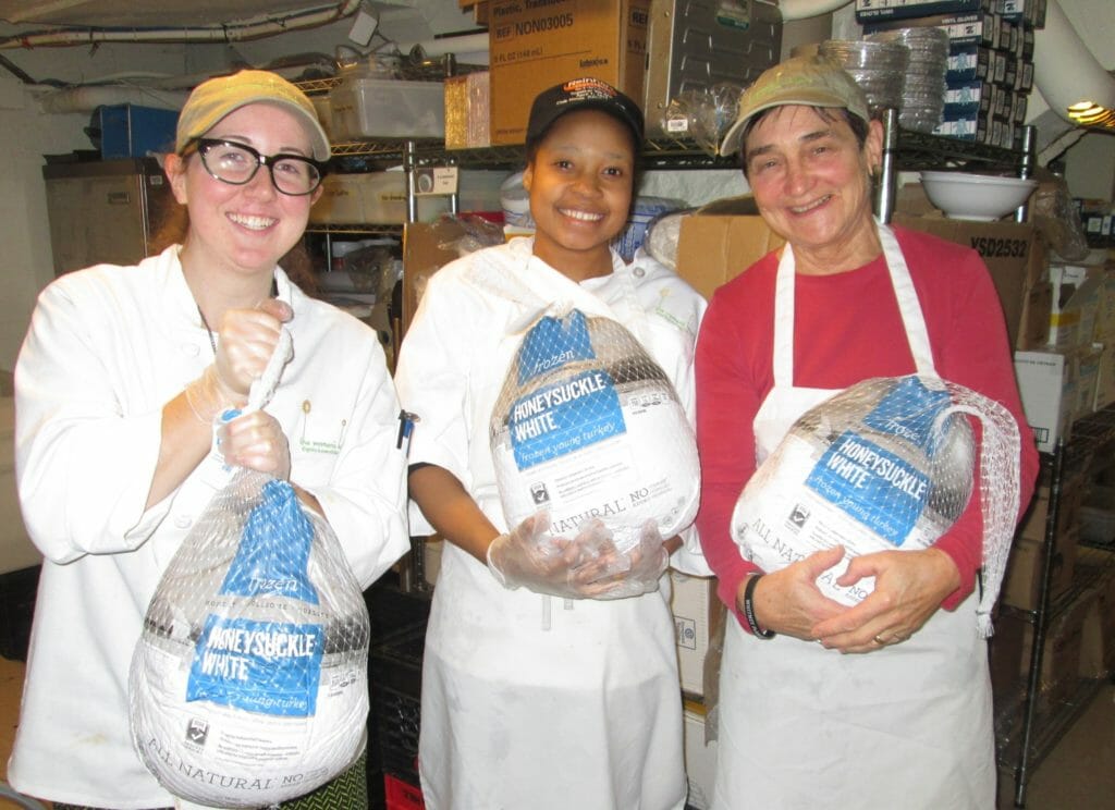 Nancy Schiefflien (right) prepping for a Thanksgiving meal with Audrey Holt (left) and kitchen assistant Jhenie Dorvil (middle)./Courtesy Women's Lunch Place