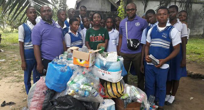 GE volunteers and students from Government Secondary School Eneka in Port Harcourt, Nigeria, stand with the recyclables they collected during the Recycle and Win competition.