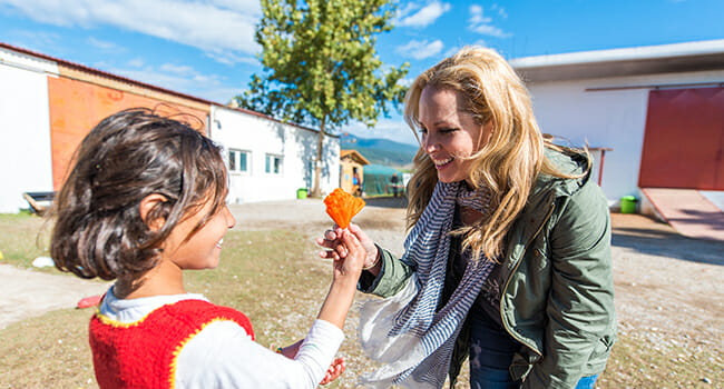 Lisa Heywood Zohn accepts a paper flower from a young refugee girl.