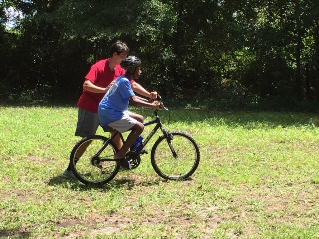 Liam teaching one of the Love A Sea Turtle campers how to ride a bike./Courtesy Liam Dao
