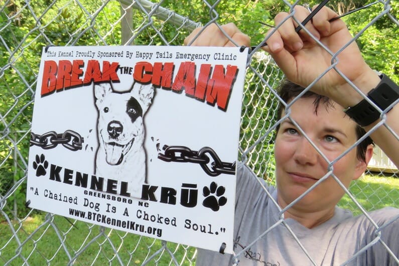 A volunteer attaches a Break the Chain Kennel Kru sign to a kennel./Courtesy Sylvia Mayon