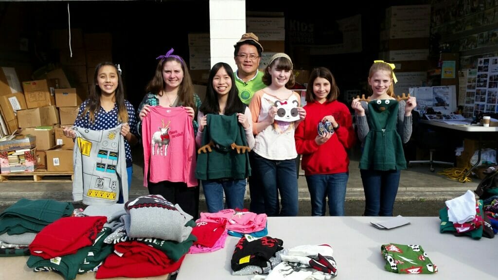 Son Michael Pham (center) and Kids Without Borders volunteers sort donated clothing at a local elementary school./Courtesy Son Michael Pham