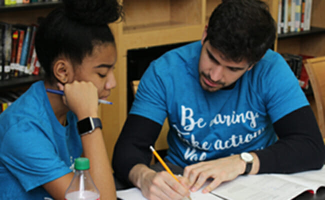 College Access volunteer reviews college preparation materials with a student.