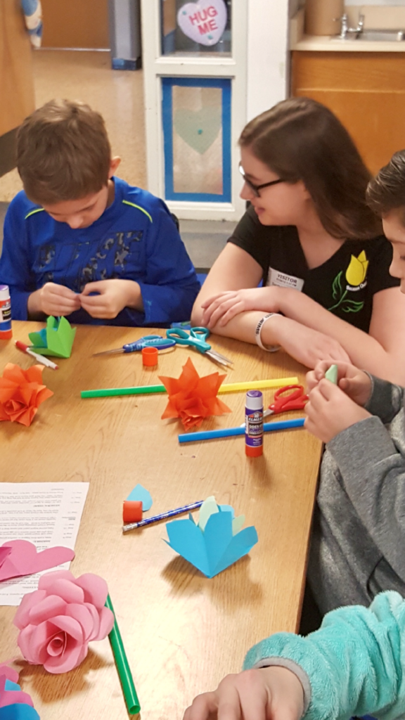 Sarah helping a student at Errick Road Elementary school as he makes flowers in Mrs. Haseley’s fifth grade class./ courtesy Sarah LoCurto