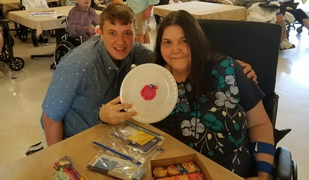 Ben Trofemuk (left) with a nursing home resident holding up a plate used in his nerf gun activity./ Courtesy Ben Trofemuk