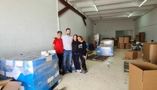 Four people posing together in a large warehouse