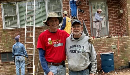 Two men standing in front of a house with construction in the background.